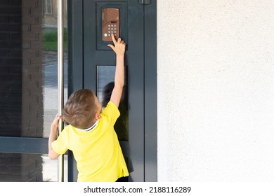 A little boy reaches for the bell to ring the doorbell, a view from the back, copy space. A child standing near the front door of the house. The child returns home.