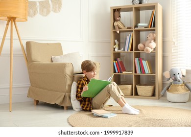 Little Boy Reading Book On Floor At Home