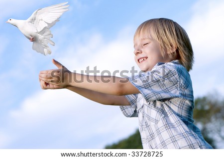 Little boy releasing a white pigeon in the sky.