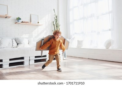 Little Boy In Retro Pilot Uniform Running With Toy Plane Indoors.