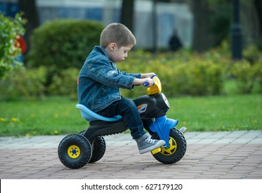 little boy ride toy motorcycle on sidewalk