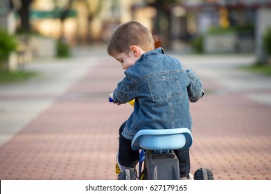 little boy ride toy motorcycle on sidewalk