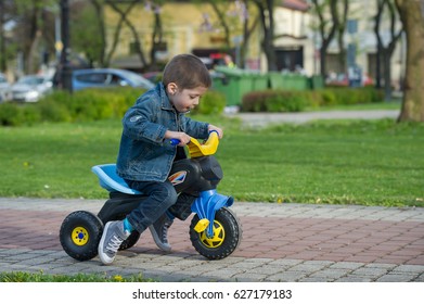 little boy ride toy motorcycle on sidewalk