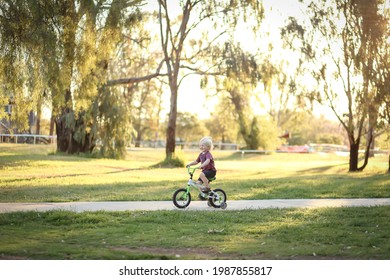 Little Boy Riding Bike Along Walking Track In Pretty Australian Bush Setting At Sunset