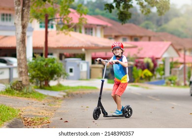 Little boy riding scooter. Kids ride kick board. Child playing on suburban street on sunny summer day. Safe helmet for children. Healthy outdoor activity. Cute kid on his way to school.
