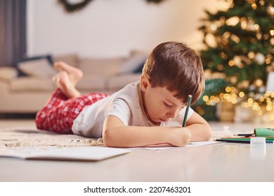 Little boy is in room with christmas tree is on the floor. - Shutterstock ID 2207463201