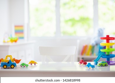 Little boy room. Desk with colorful toy cars. Nursery for young kid with educational vehicle and transport toys. Plastic car at rainbow parking garage. Home or kindergarten interior. 