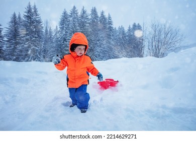 Little Boy Run On Uphill With The Sled To Go Downhill, Over The Mountain Peaks On Winter Vacation