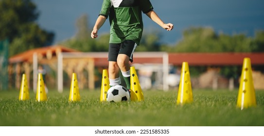Little boy running and dribbling a soccer ball at training drill with practice cones. School of football for younior level players - Shutterstock ID 2251585335