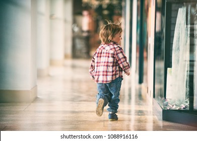 Little Boy Running In The Shopping Center. Back View.