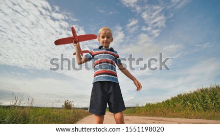 A little boy runs and launches a paralon toy airplane.
