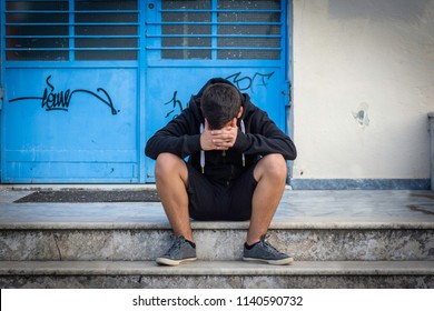 Little boy sad sitting alone at school hides his face - Powered by Shutterstock