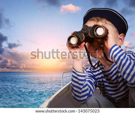Little boy in sailor's uniform with binocular in the boat