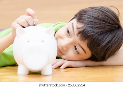 Little Boy Saving Money In Piggy Bank 