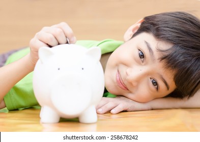 Little Boy Saving Money In Piggy Bank 