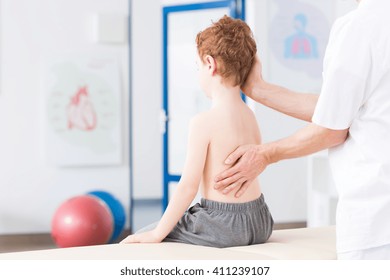 Little boy with scoliosis in rehabilitation clinic. Physiotherapist working with special method on boy's spinal column - Powered by Shutterstock