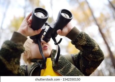 Little Boy Scout With Binoculars During Hiking In Autumn Forest. Child Is Looking Through A Binoculars. Concepts Of Adventure, Scouting And Hiking Tourism For Kids.