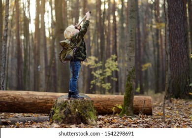 Little Boy Scout With Spyglass During Hiking In Autumn Forest. Child Is Looking Through A Spyglass. Concepts Of Adventure, Scouting And Hiking Tourism For Kids.