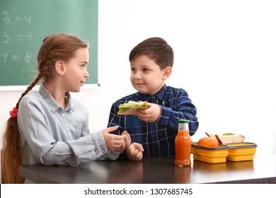 Little boy sharing his school lunch with girl in classroom