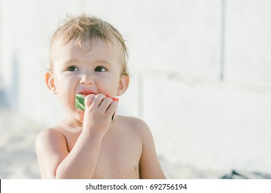 The little boy, shirtless shirtless eating watermelon while on vacation