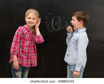 little boy shouting in drawn on the blackboard mouthpiece and little girl covering her ears with her hands