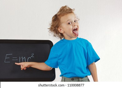 Little Boy Shows Tongue Like Einstein Near Formula On A Blackboard