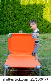 Little Boy Sits On Orange Sunbed In Outdoor 