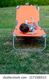 Little Boy Sits On Orange Sunbed In Outdoor 