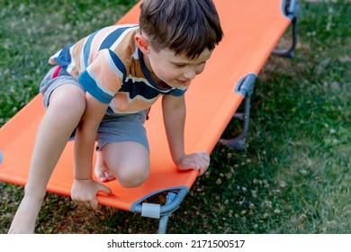 Little Boy Sits On Orange Sunbed In Outdoor 