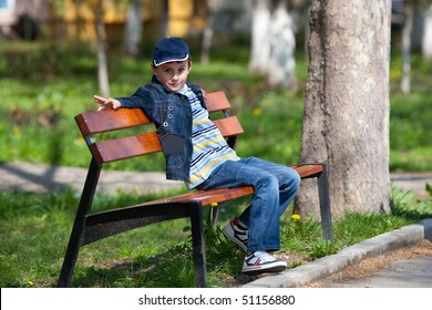 Little Boy Sitting On A Bench In Park