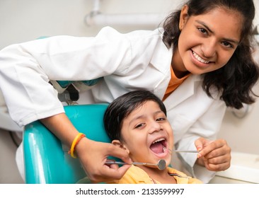 Little boy sitting on the dental chair with open mouth and a female dentist doing his oral checkup at dentist clinic. - Powered by Shutterstock