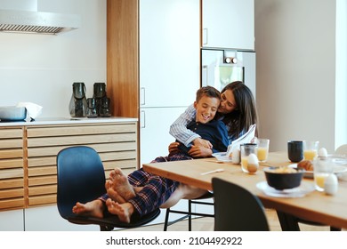 Little boy sitting on his mother's lap and reading the newspaper together at their kitchen table after breakfast in the morning - Shutterstock ID 2104492922