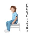 Little boy sitting on step stool against white background