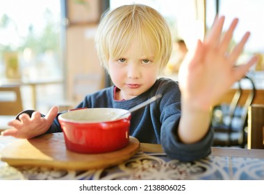 Little Boy Sitting The Table In Cafe Or Restaurant And Doesn't Want To Eat. Healthy Food. Kids Diet. Poor Appetite. Stop Gesture. Do Not Force The Child To Eat. Angry Upset Baby.