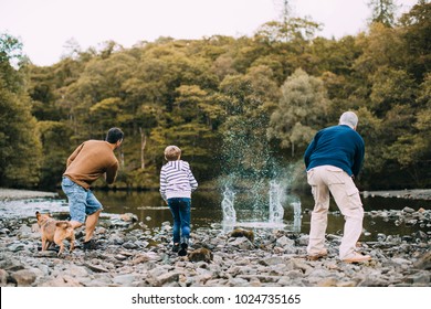 Little boy is skimming pebbles on a lake with his father and grandfather. - Powered by Shutterstock