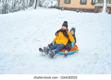 Little Boy Sledding In Winter. Child Slides Down The Mountain On A Tubing