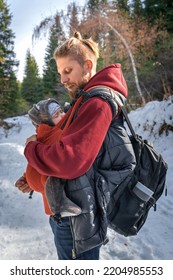 Little Boy Sleeping In His Father's Sling While Walking In The Winter Forest.