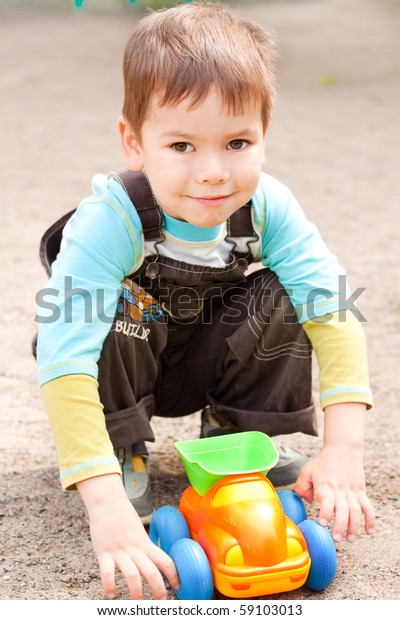 a little boy smiling and playing\
in the toy car in the children\'s village on a summer\
day