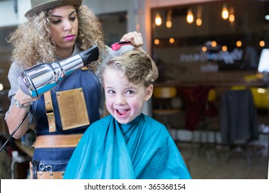 Little boy smiling while woman blowing dry his hair