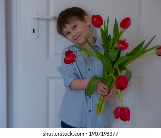 A little boy stands at the front door with a large bouquet of flowers for his mother. A gift for mom. Mothers Day - Powered by Shutterstock