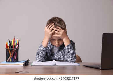 Little boy with stationery suffering from dyslexia at wooden table