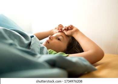 A little boy stretches after sleep while lying in bed, Morning Awakening, Sleepy child wakes up.