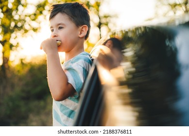 Little Boy Stuck Out His Head Of The Car For Trip, Eating Snacks During The Family Travel. Traveling On Weekend With Child. Family Enjoy Vacation Together