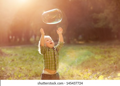 little boy in the sunset catches soap bubbles