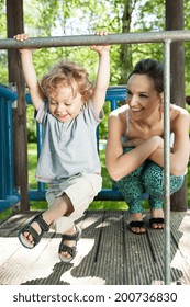 Little Boy Swinging On Monkey Bars On Playground