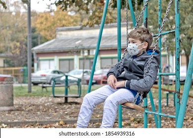 Little boy swinging at the playground while wearing face mask due to coronavirus pandemic. - Powered by Shutterstock