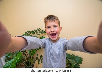 little boy takes a selfie with both hands on a wide lens of a smartphone. photo on the page. happy boy. selfie kids.