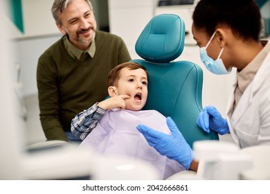 Little boy talking about his toothache with dentist while being with his father at dental clinic.  - Powered by Shutterstock