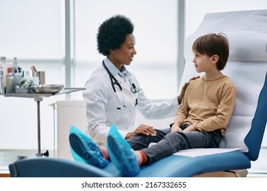 Little Boy Talking To African American Pediatrician During Medical Exam At Doctor's Office.