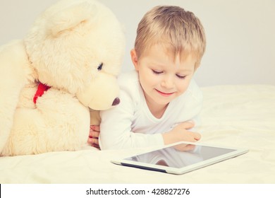 little boy and teddy bear looking at touch pad - Powered by Shutterstock